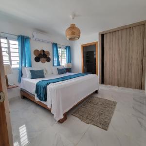 a bedroom with a large bed with blue curtains at TropicalvacationvillaEYS in Punta Cana