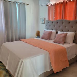 a bedroom with a large bed with an orange curtain at TropicalvacationvillaEYS in Punta Cana