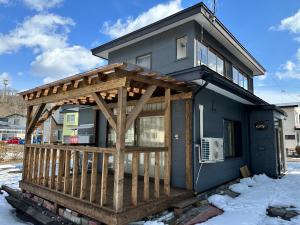 uma casa com um deque de madeira na neve em Mint / 11min walk to Noboribetsu st em Noboribetsu