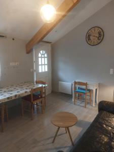 a living room with a table and chairs and a clock at L'Orangerie Pau Idron in Idron