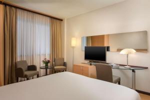 ヴィッラノーヴァにあるNH ボローニャ ヴィラノヴァのベッドとテレビが備わるホテルルームです。