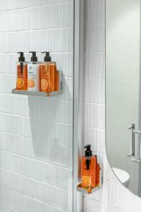 La salle de bains est pourvue d'une étagère avec des produits orange et d'un miroir. dans l'établissement The Public Ortakoy, à Istanbul