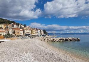 a sandy beach with buildings and the water at Villa Visum Mare Unus in Mošćenička Draga