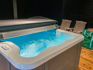 a hot tub with blue water in it with two chairs at Holiday Home Villa kaislaranta by Interhome in Iitti