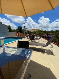 a swimming pool with chairs and an umbrella at Recanto Fiel in Itacaré