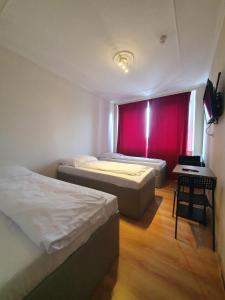 duas camas num quarto com uma cortina vermelha em R&B Hotel em Berlim