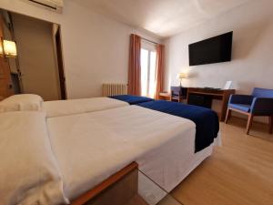 a hotel room with a large bed and a desk at Hotel Sant Jordi in Tarragona