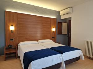 a bedroom with two beds and a wooden wall at Hotel Sant Jordi in Tarragona