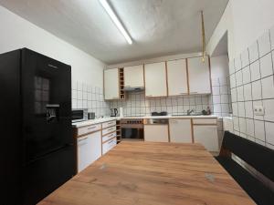 eine Küche mit einem schwarzen Kühlschrank und einem Holztisch in der Unterkunft Monteurzimmer Im Kraichtal! By Simplex in Kraichtal