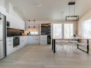a kitchen with white cabinets and a table with chairs at Holiday Home Palanteen haavelinna by Interhome in Eräjärvi