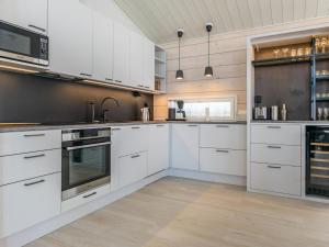 a kitchen with white cabinets and stainless steel appliances at Holiday Home Palanteen haavelinna by Interhome in Eräjärvi