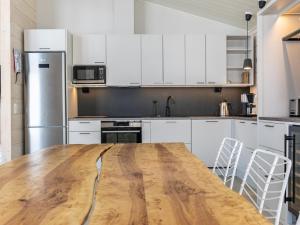 a kitchen with a wooden table and white cabinets at Holiday Home Palanteen haavelinna by Interhome in Eräjärvi