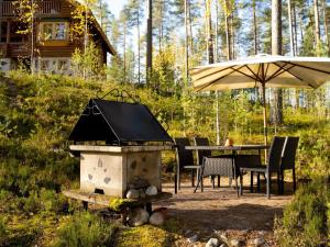 a grill with a table and an umbrella in a yard at Holiday Home Villa tunturitervakko by Interhome in Ylämylly