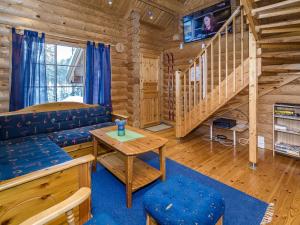 a log cabin living room with a couch and stairs at Holiday Home Villa tunturitervakko by Interhome in Ylämylly