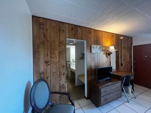 a room with a desk with a computer and a bedroom at Nocturne Motel in New Smyrna Beach