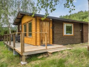 a wooden cabin with a deck in the grass at Holiday Home Nilla 3 by Interhome in Utsjoki
