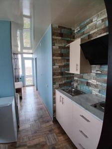 a kitchen with white cabinets and a brick wall at Hotel Kobuleti in Kobuleti