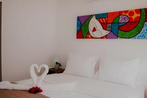 a bedroom with two swans on a bed with a painting at Familia Pansini casa na Pipa in Pipa