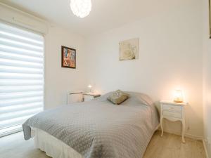 a white bedroom with a bed and a window at Apartment Les Rives de la Rance by Interhome in La Richardais
