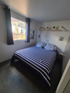 a bedroom with a bed with blue and white stripes at o fil de l'eau in Omessa