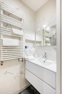 a white bathroom with a sink and a mirror at Appartement Puteaux la Defense in Puteaux +4 photos