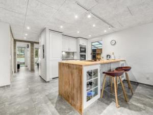a kitchen with white cabinets and a wooden island with stools at Holiday Home Elisabetha - 100m from the sea in Western Jutland by Interhome in Esbjerg