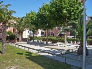 un parco con panchine e palme e un edificio di Holiday Home Les Coraux-13 by Interhome a Canet-en-Roussillon