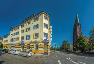 un edificio amarillo con coches estacionados frente a una calle en City Hotel en Bremerhaven