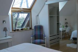 um quarto com uma janela, uma cadeira e uma secretária em La Villa sous Les Pins em La Trinité-sur-Mer