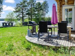 eine Terrasse mit einem Grill und Stühlen auf einem Haus in der Unterkunft Holiday Home Wooden ecovilla by Interhome in Haapalahti