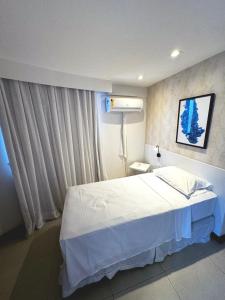 a bedroom with a white bed and a window at Deluxe Rooms By Booking Fortaleza in Fortaleza
