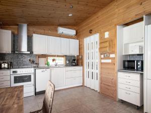 a kitchen with white cabinets and a wooden ceiling at Holiday Home Ketunkolo by Interhome in Tampere