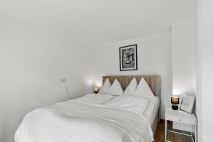 een slaapkamer met een bed met witte lakens en 2 lampen bij StayEasy Apartments Leoben P88 #11 in Donawitz