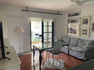uma sala de estar com uma mesa de vidro e um sofá em Apartamento premium un dormitorio ALCAUDON na Isla Canela