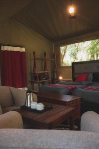 um quarto com duas camas, uma mesa e um sofá em Drunken Elephant Mara em Sekenani