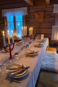 a long table with candles and plates and napkins at Holiday Home Laattajan hirsipirtti by Interhome in Hyrynsalmi