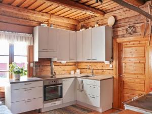 a kitchen with white appliances and a wooden wall at Holiday Home Laattajan hirsipirtti by Interhome in Hyrynsalmi