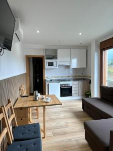 a living room with a wooden table and a kitchen at Top Sanxenxo Resort in Sanxenxo