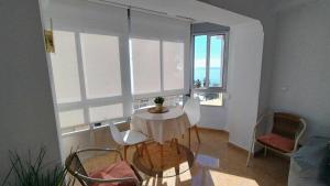 a table and chairs in a room with windows at Hoja Calá Apartment in Algarrobo-Costa