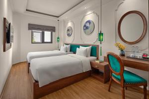 um quarto com 2 camas, uma secretária e um espelho. em Eliana Premio Hotel Hanoi em Hanói