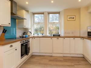a white kitchen with white cabinets and windows at Holiday Home Railway House by Interhome in Aviemore