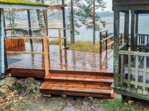 una terraza de madera en una casa con vistas al agua en Holiday Home Utras by Interhome, en Punkaharju