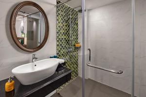 ein Bad mit einem Waschbecken und einer Dusche mit einem Spiegel in der Unterkunft Eliana Premio Hotel Hanoi in Hanoi