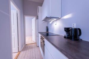 uma cozinha com paredes brancas e um balcão preto em Maya Apartments - Sentrum em Oslo