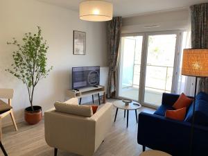 uma sala de estar com um sofá e uma televisão em Domitys Villa Kera em Limoges