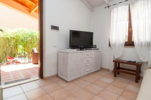a living room with a television and a sliding glass door at Pula - Villetta a 100m dal mare in Fort Village