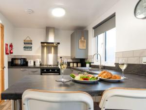 a kitchen with a table with a plate of food and wine glasses at Chalet Wheal Rose by Interhome in Helston