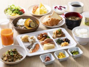 a table with plates of food and bowls of food at Hotel Wing International Kobe - Shinnagata Ekimae in Kobe