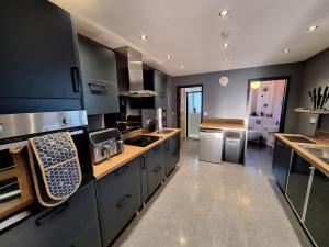 a large kitchen with black cabinets and stainless steel appliances at Rare Wood-Fired Hot Tub 2 Bed Get Away In Norfolk in Norwich