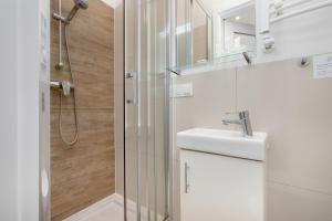 a white bathroom with a shower and a sink at Cosy Studios near the Old Town in Gdańsk by Renters in Gdańsk
